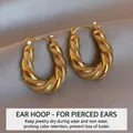 Vintage golden twisted hoop earrings with a textured scale pattern finish on grey fabric - Gold