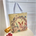 Detail view of a beige canvas tote bag featuring an embroidered floral rabbit design - Flower Bush Rabbit