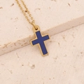 Makroaufnahme Goldene Kreuzkette mit tiefblauem Emaille-Inlay auf beigem Steinboden - Blaues Kreuz (1#)