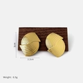 Golden geometric shell-style earrings with vertical brushed texture on a wood display - Gold Crossed Ring