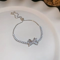 Macro shot of silver bow bracelet with zircons on white tray in soft lighting - Silver