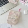 Detail van roze geruite make-uptas met bubbeltextuur en zijden decoratieve strikken - Lichtroze