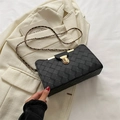 Minimalist black woven shoulder bag with gold clasp and chain strap on chic blazer - Black