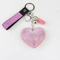Detailed view of pink heart keychain with glittering rhinestones and tassel accent - Pink