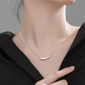 Minimalist silver titanium steel necklace featuring a polished curved bar pendant on a model - Steel