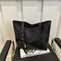 Large black tote bag with crocodile pattern and glossy finish on a designer chair - Black
