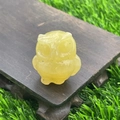 Translucent yellow natural stone owl figurine on wood base with outdoor background - Golden Steatite
