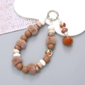 Brown beaded phone wristlet with plush ball and matte pearls for winter style - Brown Pompom Pendant Style (K2670)