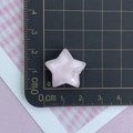 Dettaglio stella in resina rosa glitterata con misura di 2,5 cm su tappetino graduato - Stella Rosa Glitterata