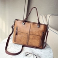 Vintage brown leather tote bag with dual front pockets and shoulder strap on table - Dark Brown
