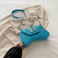 Blue glitter crossbody bag with metal bow detail and chain strap on a beige blazer - Blue