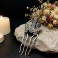 Macro shot of a bohemian moon hair comb with black crystal stones on a natural rock surface - Obsidian