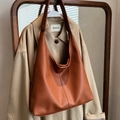 Bolso tote de cuero marrón con textura de lichi colgado en una gabardina beige - Marrón