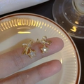 Eleganti orecchini a perno con fiocco e stella in oro con zirconi in un ambiente accogliente - Oro