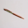 Detail of rose gold ballpoint pen featuring green crystal stones in a clear barrel - Peridot