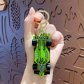 Vibrant green formula car keychain with black wheels and golden ring on a wooden background - Green