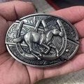 Close-up of vintage silver belt buckle with 3D embossed horse and horseshoe patterns - Horseshoe Running Horse