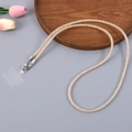 Close-up of golden woven mobile phone lanyard with metal clasp on a wooden tray - Champagne