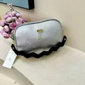 Detail of silver textured leather camera bag featuring wavy black shoulder strap and gold hardware - Silver