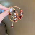Detailed close-up of woven C-shaped earrings with colorful sandalwood beads and gold metal - Brown Bead Tassel