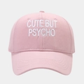 Close-up of pink cotton baseball cap with white Cute But Psycho embroidery text - Pink