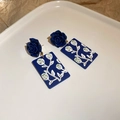 Dettaglio degli orecchini rosa blu scuro con pendente a girasole artistico su vassoio bianco - Stile Rosa Blu / Blu scuro