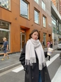 Elegant light gray cashmere-feel scarf with tassels worn over a long black winter coat - Pure White