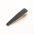 Detail showing cow print pattern and gold metal base of the stylish hair clip - Black Texture