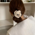 Detail of a beige camellia flower scrunchie with black trim on a ponytail - Hair Tie / White