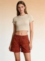 Dettaglio del crop top in maglia a coste beige e pantaloncini rosso mattone rifiniti - S / Caramello