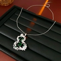 Détail macro du pendentif gourde vintage argenté avec pierres vertes sur cuir noir - Argent Vert
