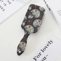 Detalle del cepillo para el cabello con diseño de calavera vintage y flores en negro - Fondo Negro Tres Calaveras