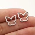 Macro shot of silver butterfly stud earrings on a finger showing scale and detail - 670 Hollow Winged Butterfly / Steel
