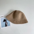 Detail of caramel cable knit bucket hat with textured patterns on a neutral background - Camel