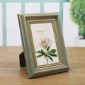 European vintage bronze and gold photo frame with floral insert on a wooden desk - Blue Gold