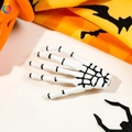 Close-up of white skeleton hand hair clip with Halloween pumpkin and spider background - White