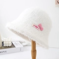 Detail of soft white plush bucket hat featuring a 3D pink bow and fluffy fur texture - White