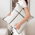 Minimalist white PU leather cushion with black geometric piping held by a model - White Patchwork Leather Pillow Cover