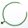 Detail of gold necklace with green heart-shaped cubic zirconia on a white surface - Gold Green Zirconia Necklace