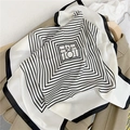 Macro detail of silk scarf with black and white stripes draped on a wooden hanger - White Striped