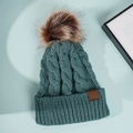 Close-up of cable knit texture on a dark green beanie with a brown faux fur pom-pom - One Size / Blue Gray