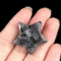 Pietra di labradorite naturale lucidata a forma di stella tenuta in mano su nero - Lampo Nero (Labradorite)