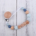 Close-up of silicone and beech wood pacifier clip with baby letter beads on wood background - Grey Blue