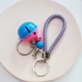 Detail of pink and blue bell keychain with braided rope and metal ring on ceramic plate - Blue Rose