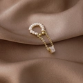 Detail van een parel ear cuff met gouden kwastjes en zircon op een bruine zijden stof - Vierkante Zirkonia Stijl