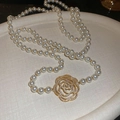 Détail d'un collier de perles orné d'un pendentif rose doré serti de cristaux étincelants - Doré