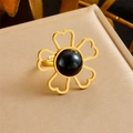 Macro detail of gold flower ring with black gemstone and heart petals on beige leather - Hollow Heart Black Stone Style (R468)
