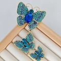 Vintage gold brooch with three blue crystal butterflies on a beige jewelry display tray - Triple Butterfly Drop-Blue