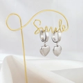 Detail view of silver heart drop earrings hanging on a decorative gold metal smile display - Silver Heart Pendant Earrings