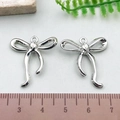 Pair of silver-tone hollow bow metal pendants on a white surface with measurement ruler - Curved Bowknot - Silver (21403)